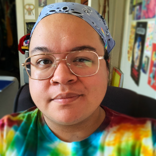 A Filipino person wearing glasses and a bandana smiles at the camera.