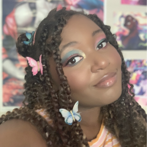 A Black woman with long braided hair smiles at the camera.